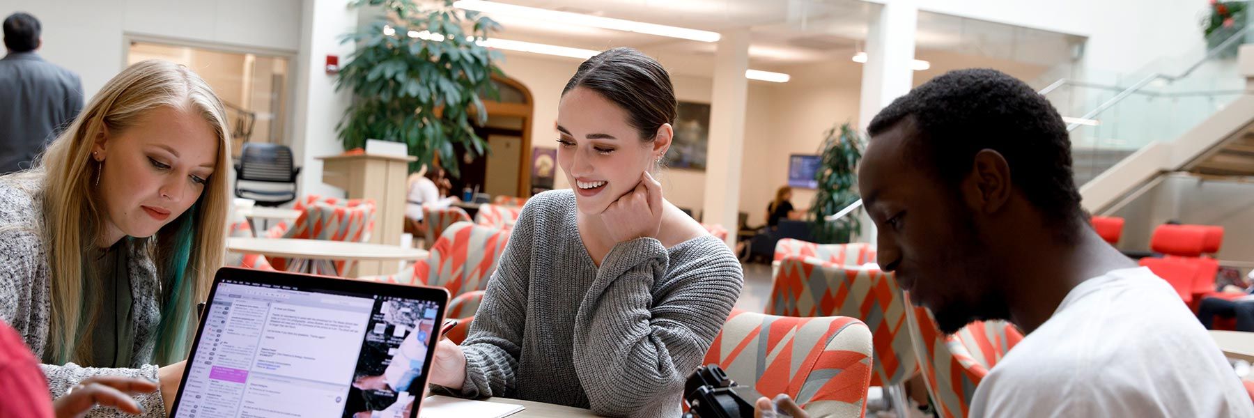Three students work at a table in the central commons of Franklin Hall.