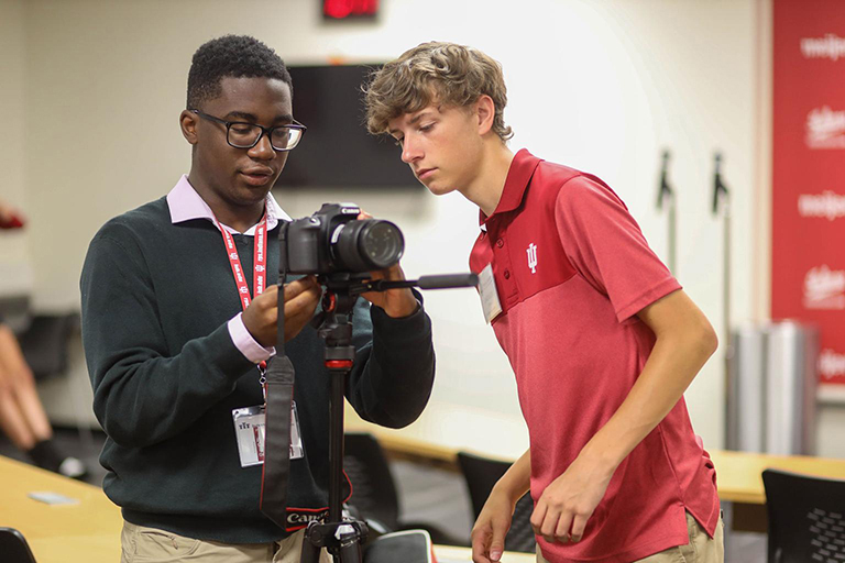 Two students work with a camera during the High School Journalism Institute.