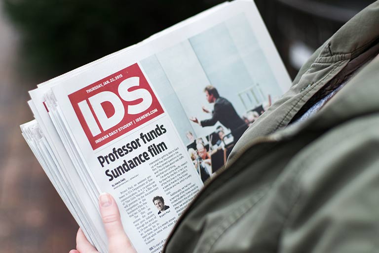 A person's hands holding a stack of IDS newspapers