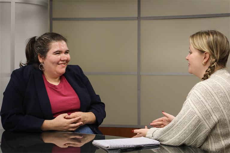 Ellen Hine sits at a table chatting with Emerson Elledge.
