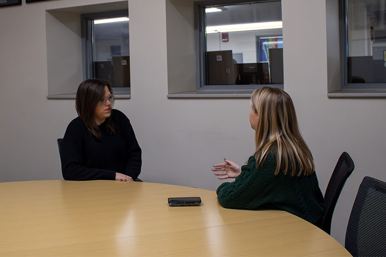 MJ Slaby sits at a table talking to Emerson Elledge.